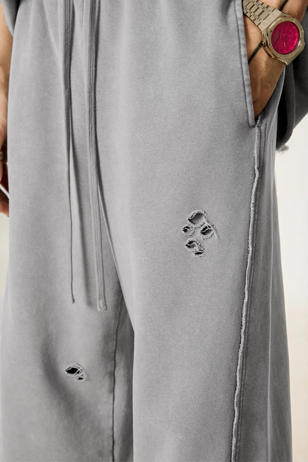 Gray pants with distressed details on a plain background