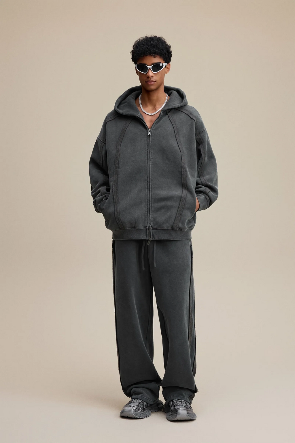 Person wearing a gray hoodie and pants on a beige background