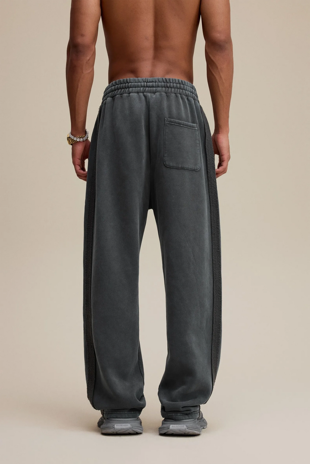 Person wearing gray sweatpants on a beige background