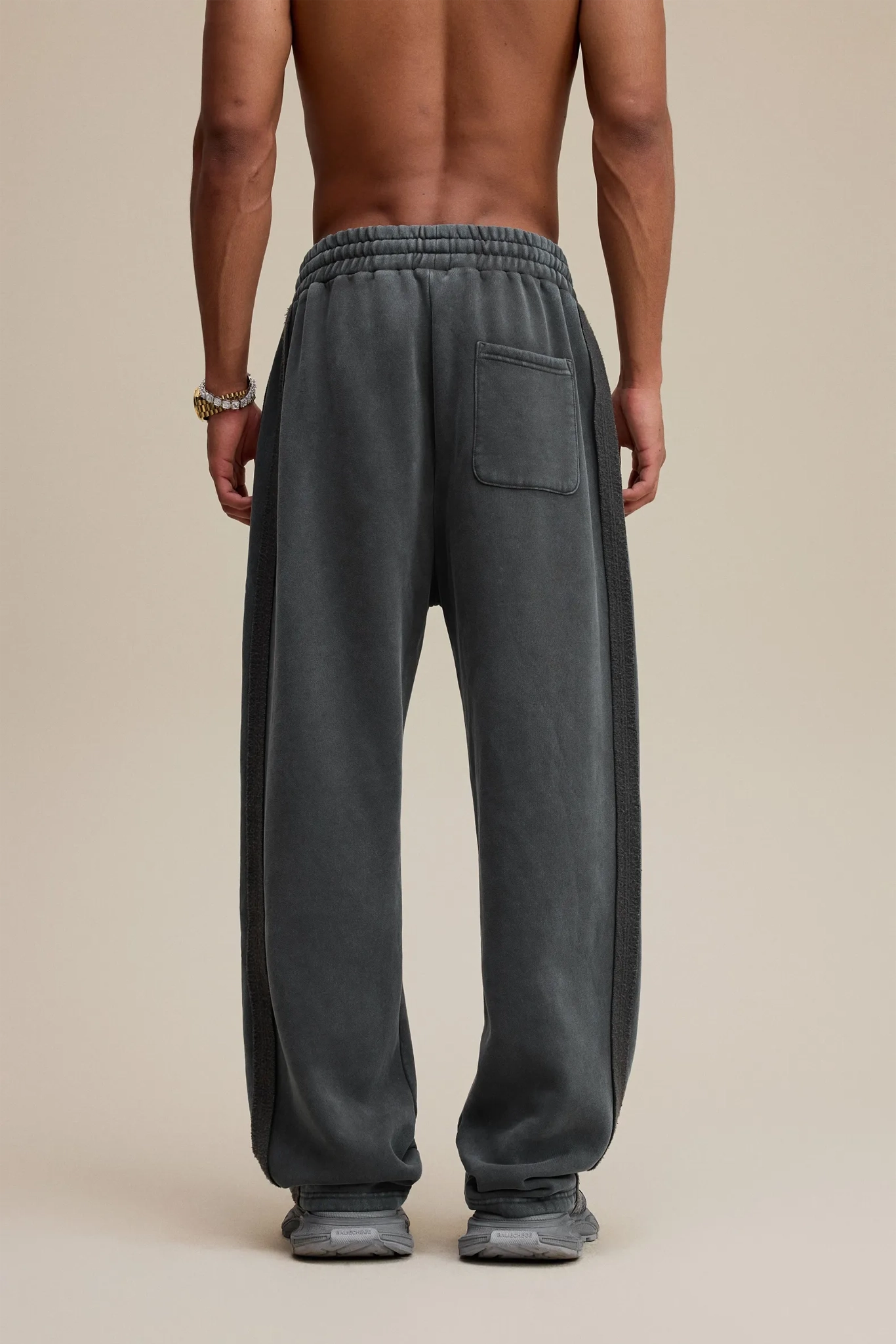Person wearing gray sweatpants on a beige background