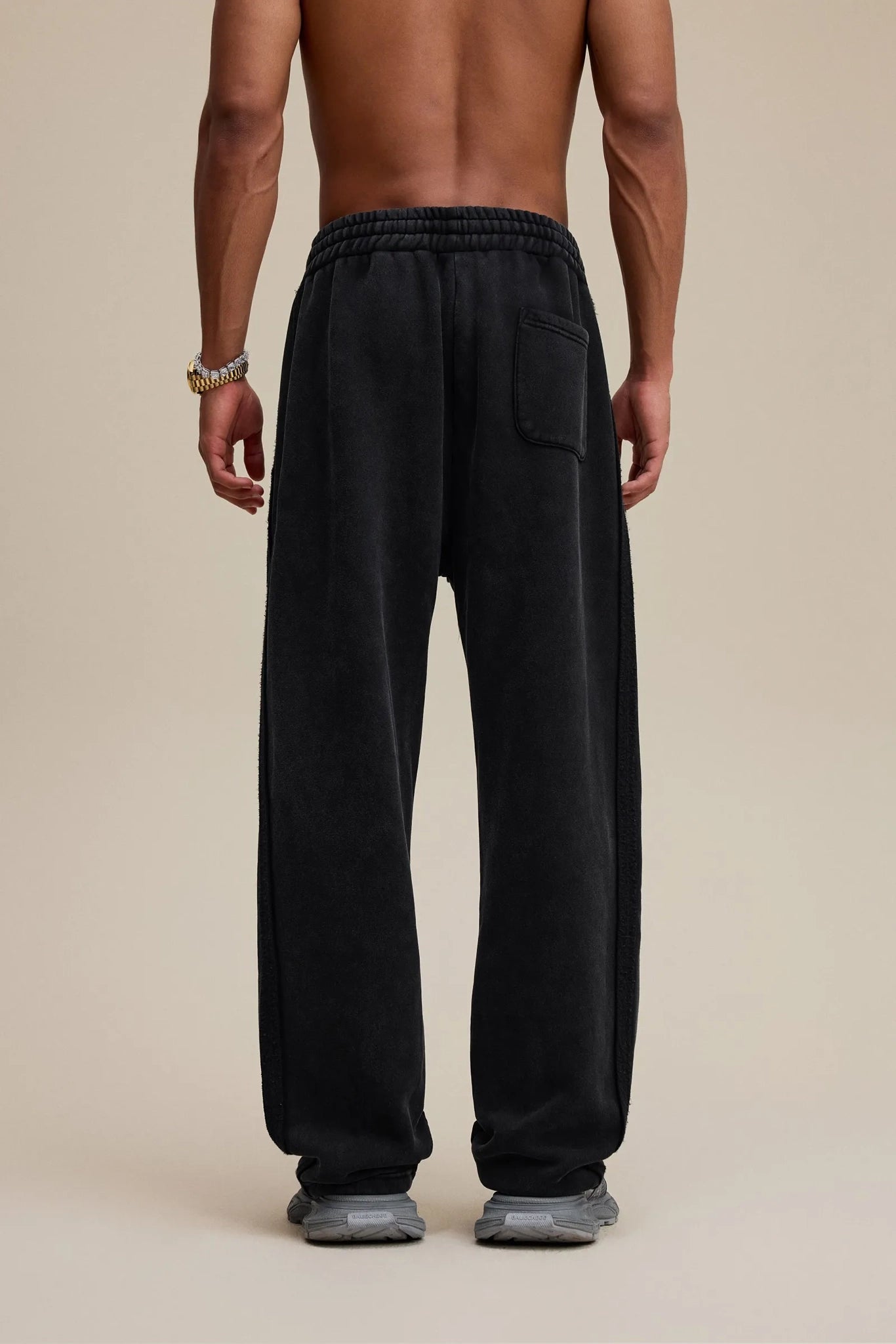 Person wearing black cargo pants on a beige background