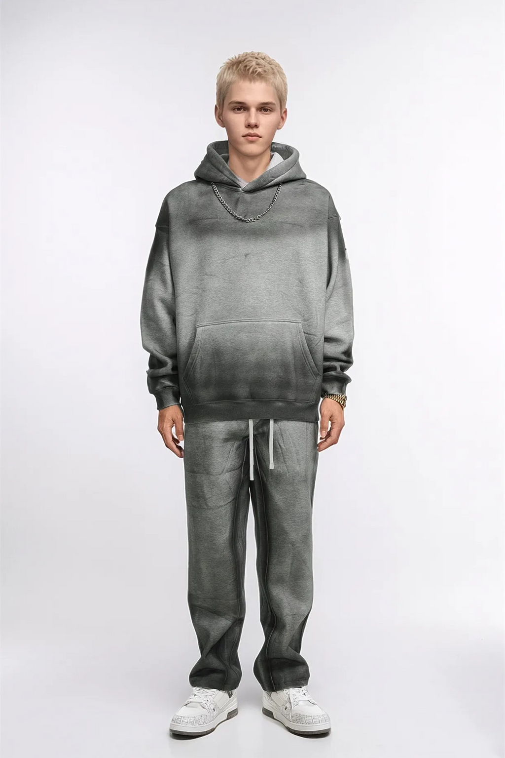 Person wearing a gray hoodie and pants set on a white background