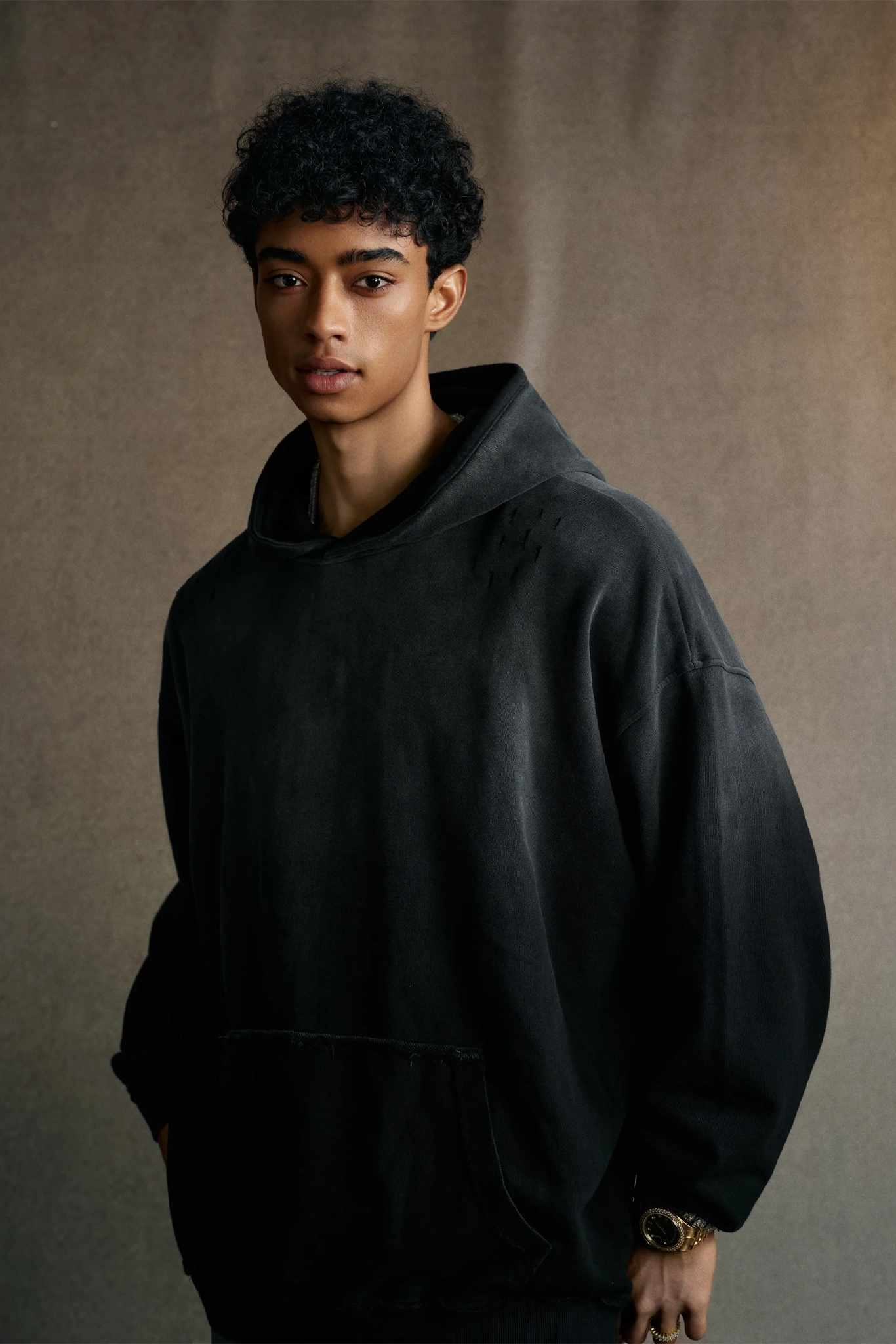 Person wearing a black hoodie against a brown background