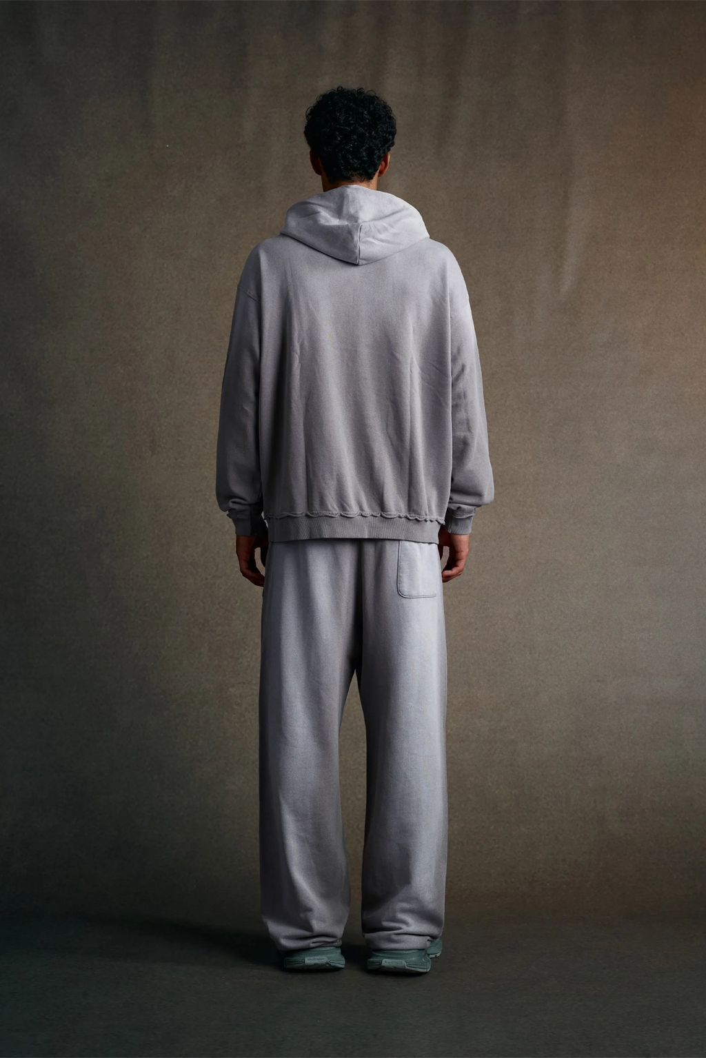 Person wearing a gray tracksuit standing against a plain background