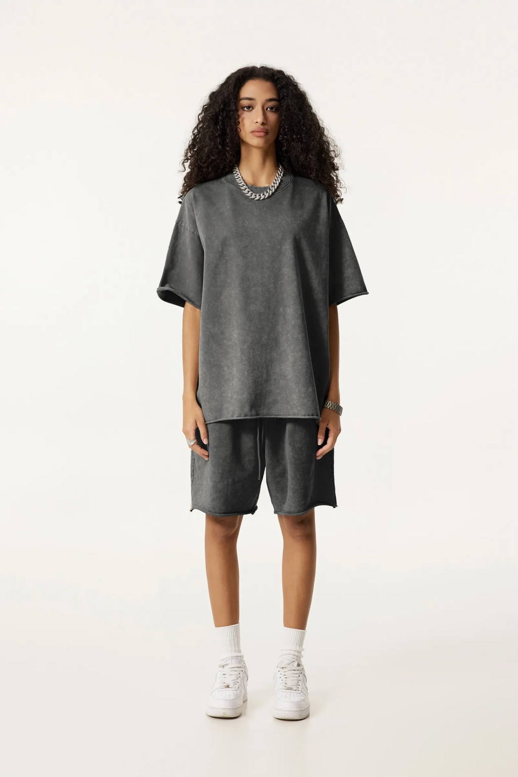 Person wearing a gray oversized t-shirt and shorts set on a white background