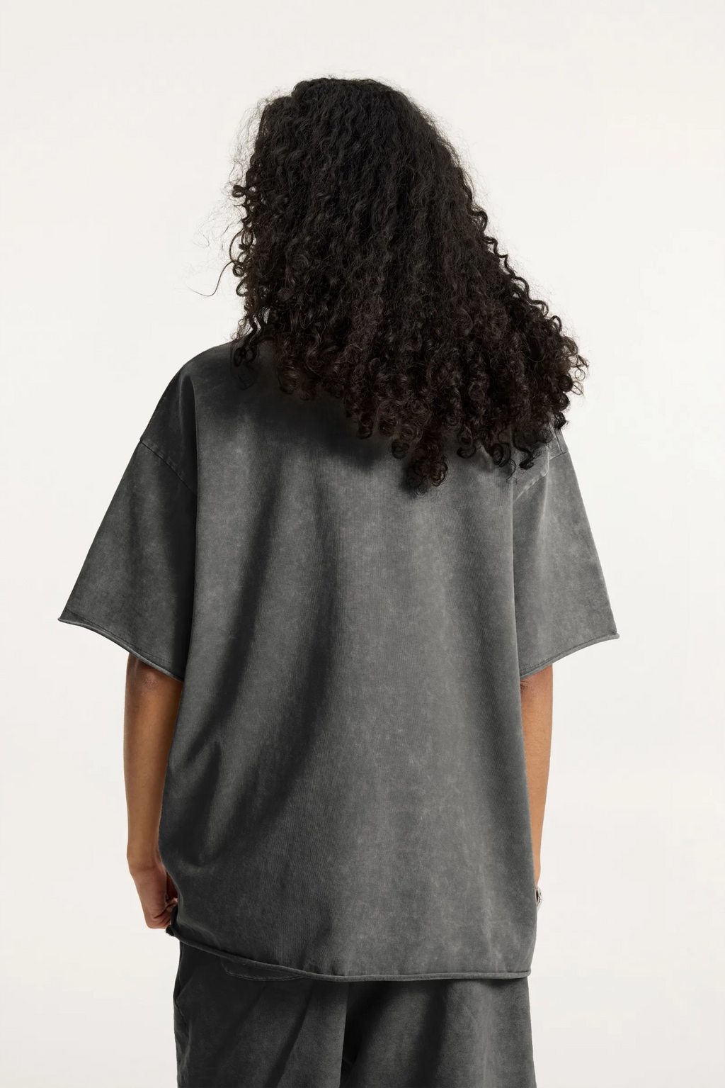 Person wearing a gray oversized t-shirt on a white background