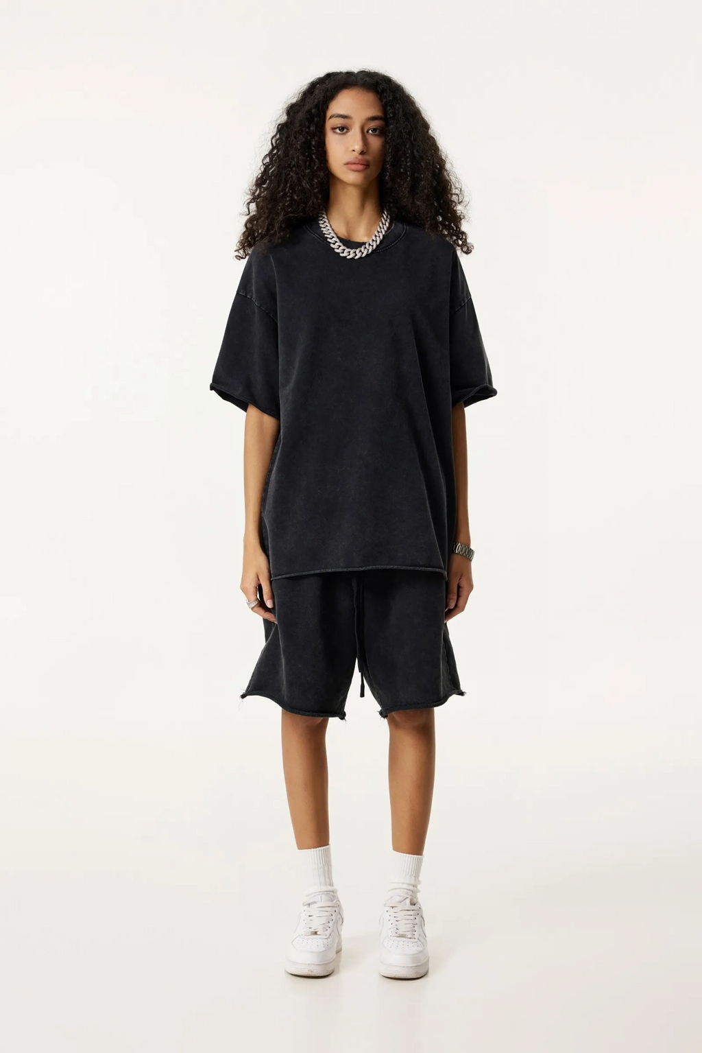 Person wearing a black outfit with white sneakers on a white background