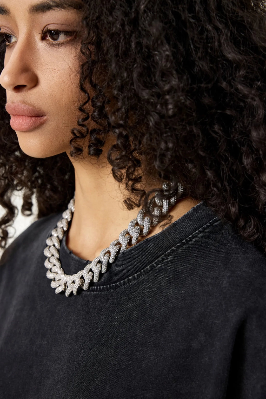 Close-up of a person wearing a textured necklace with a dark background