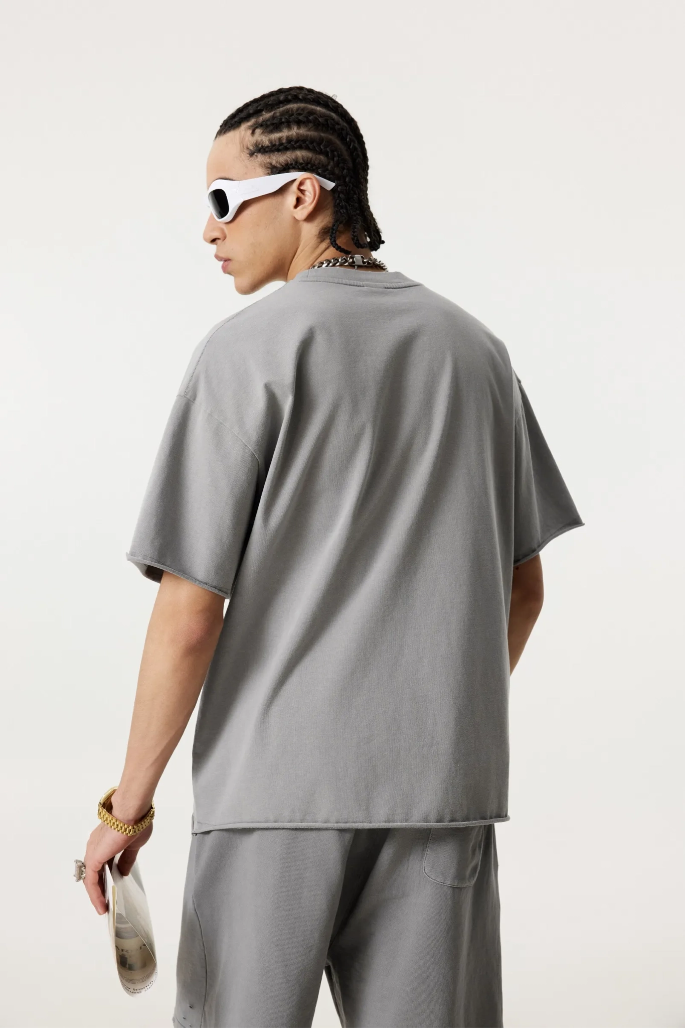 Person wearing a gray outfit with sunglasses on a white background