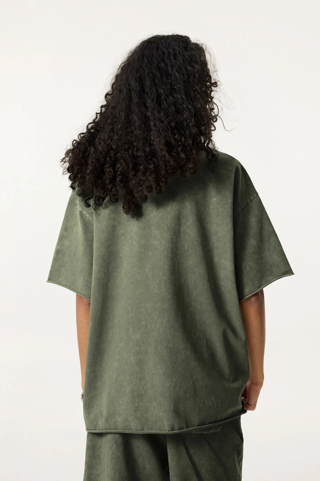 Person wearing a green oversized t-shirt and pants on a white background