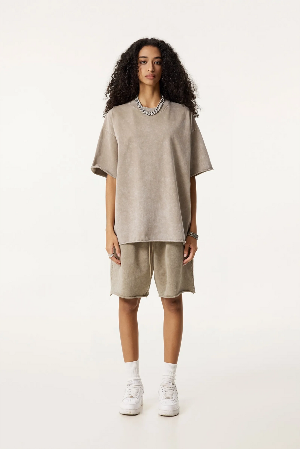 Person wearing a beige oversized sweater and shorts set on a white background