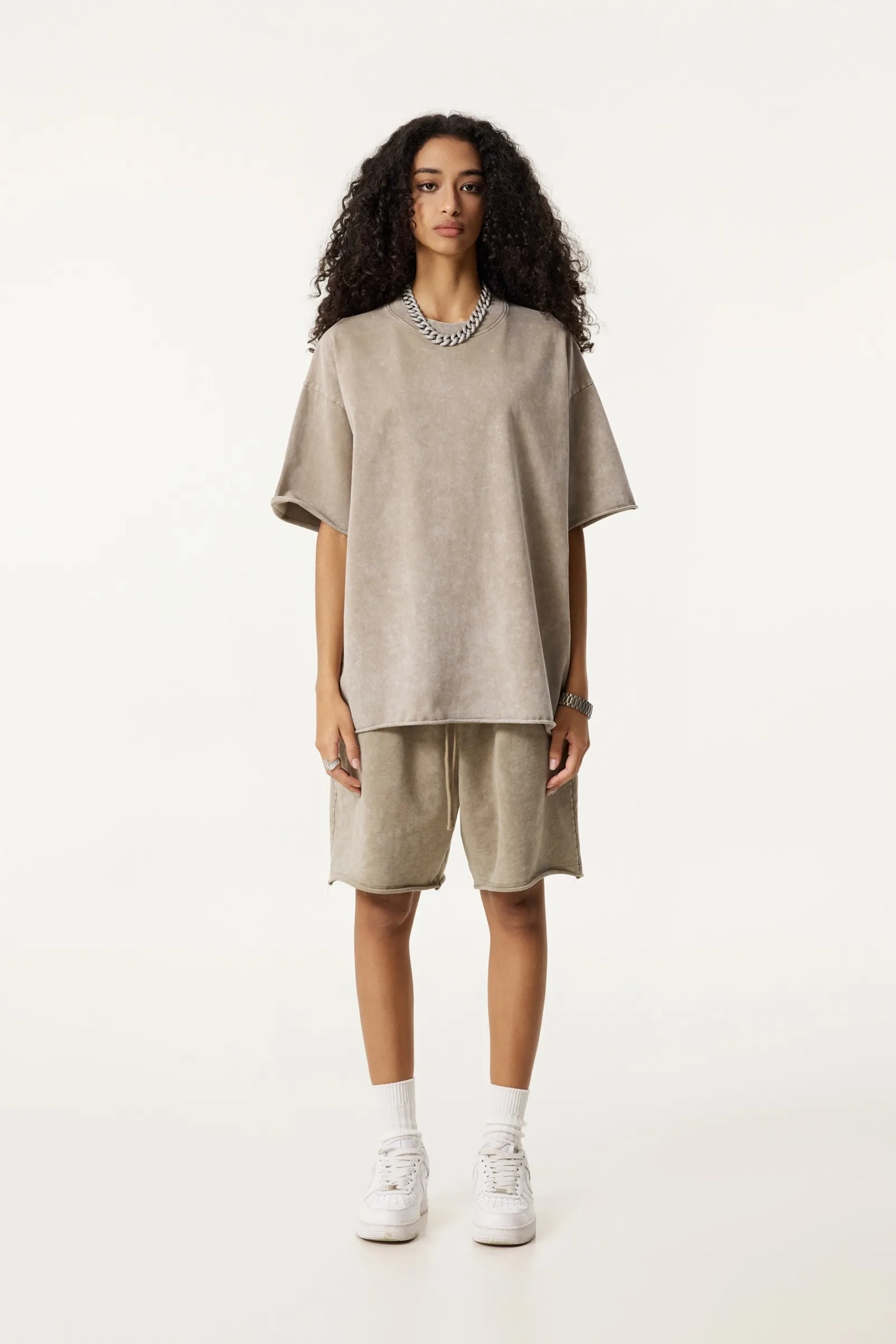 Person wearing a beige oversized sweater and shorts set on a white background