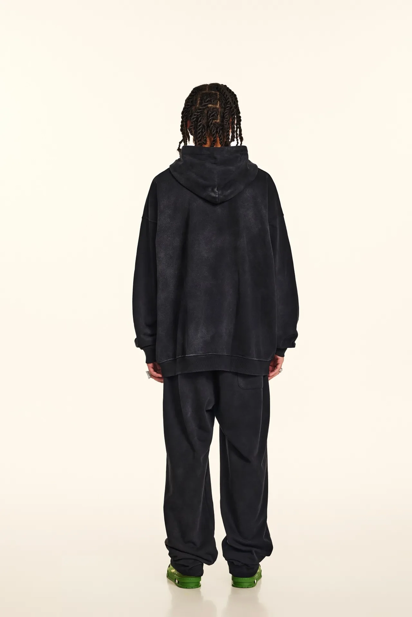 Person wearing a black hoodie and pants on a white background