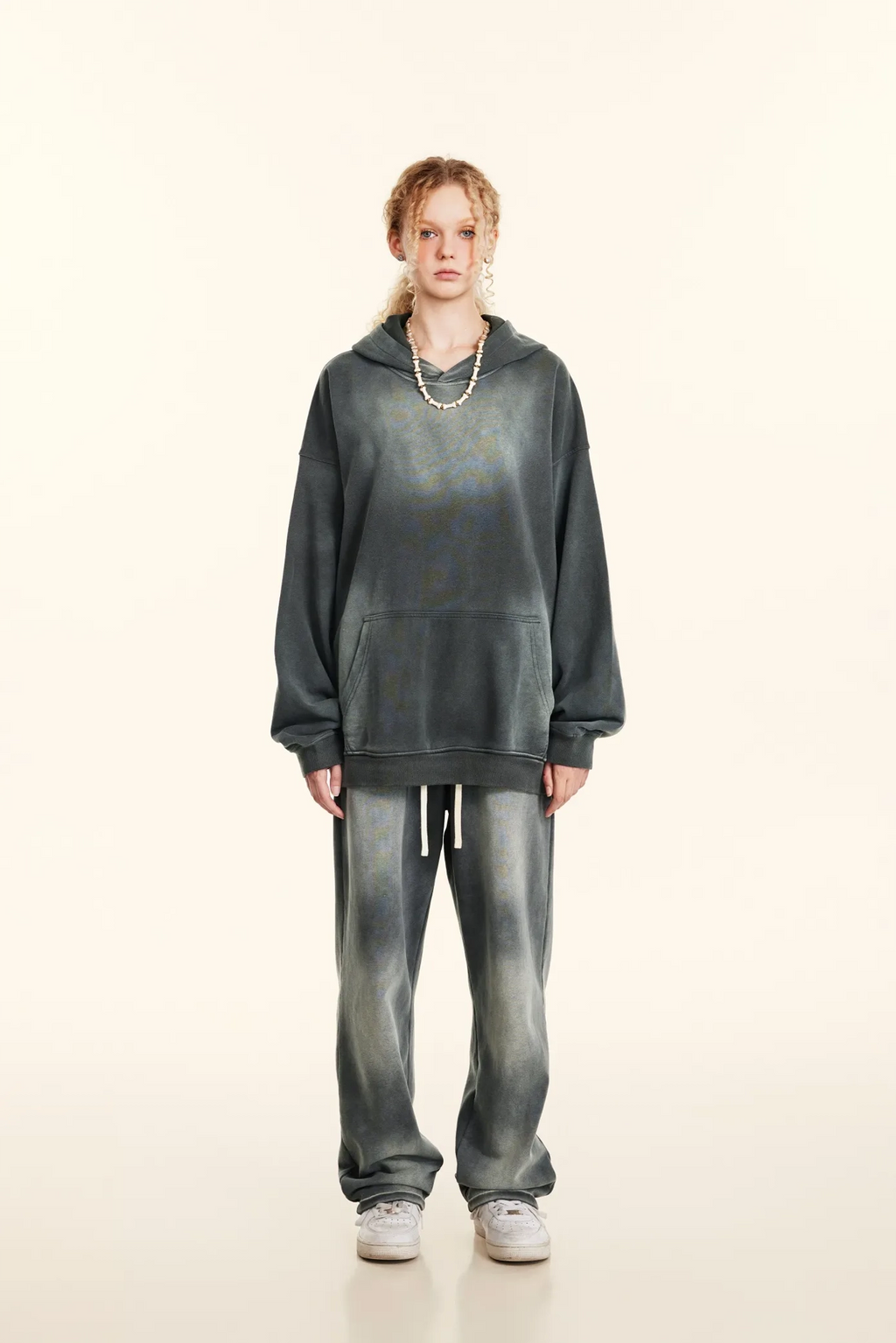 Person wearing a gray hoodie and jeans on a white background