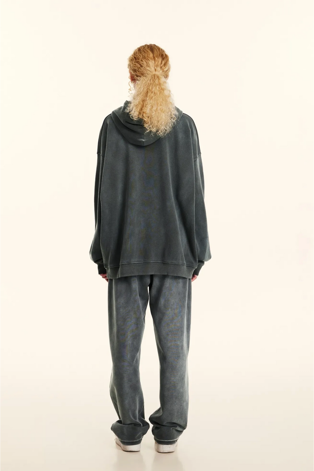 Person wearing a dark gray hoodie and pants on a white background