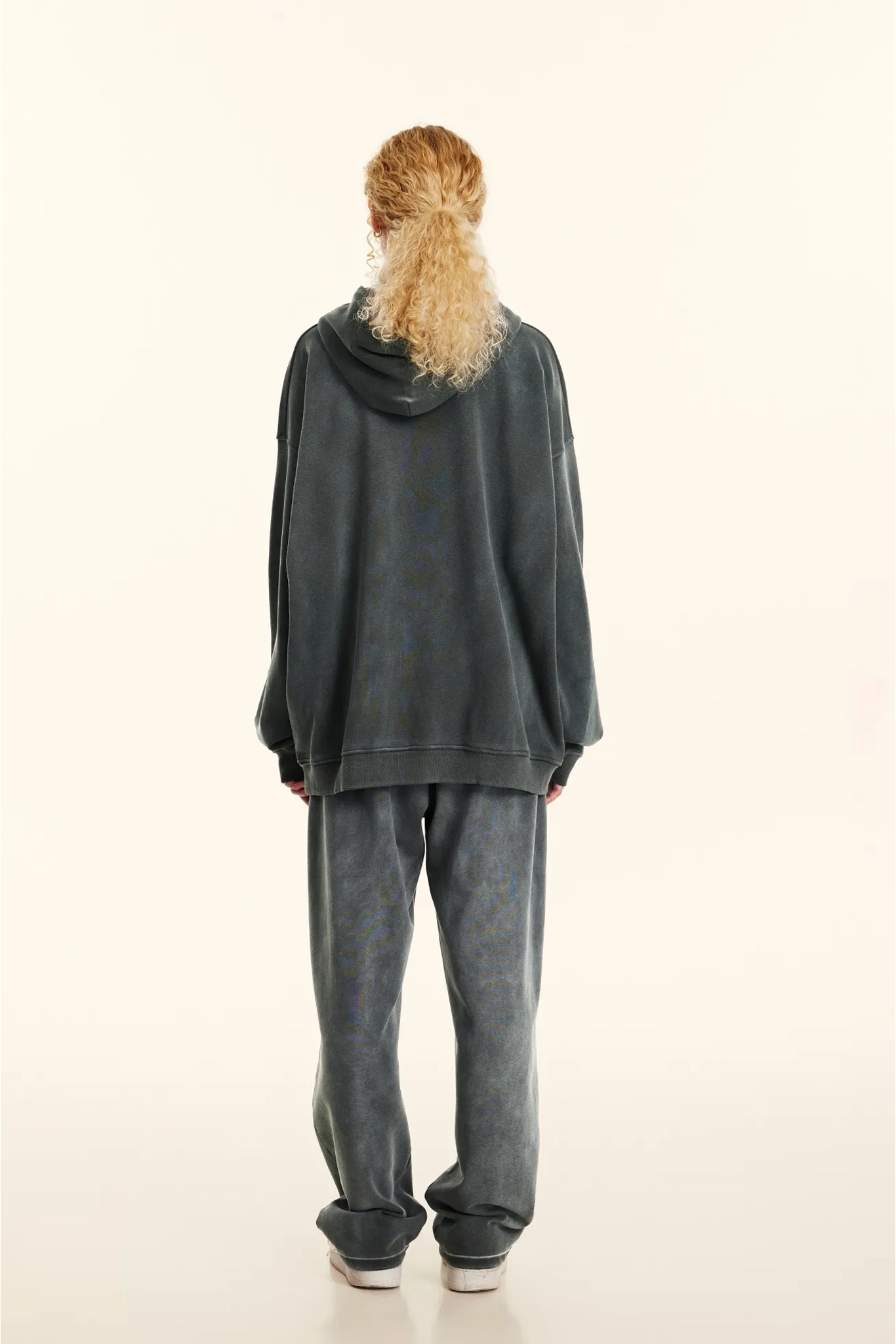 Person wearing a dark gray hoodie and pants on a white background