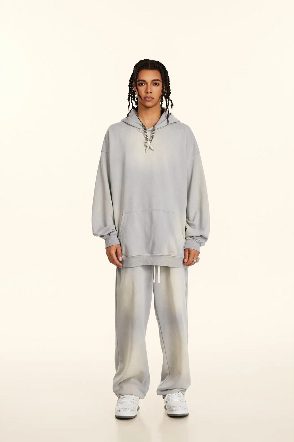 Person wearing a gray hoodie and pants on a white background