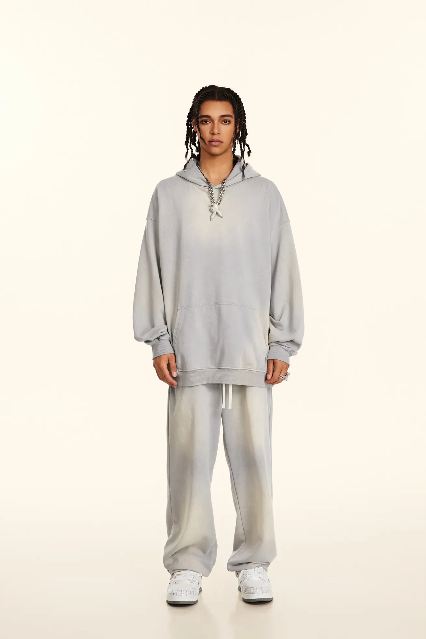 Person wearing a gray hoodie and pants on a white background