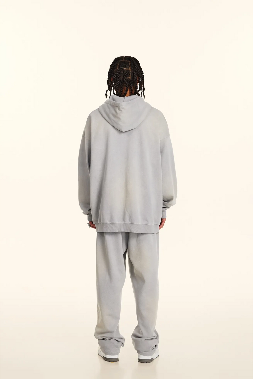 Person wearing a light gray hoodie and pants on a white background