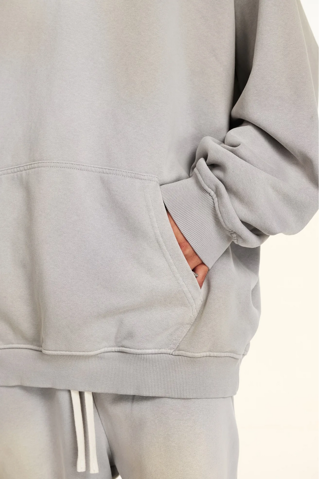 Gray tracksuit with white drawstrings on a light beige background