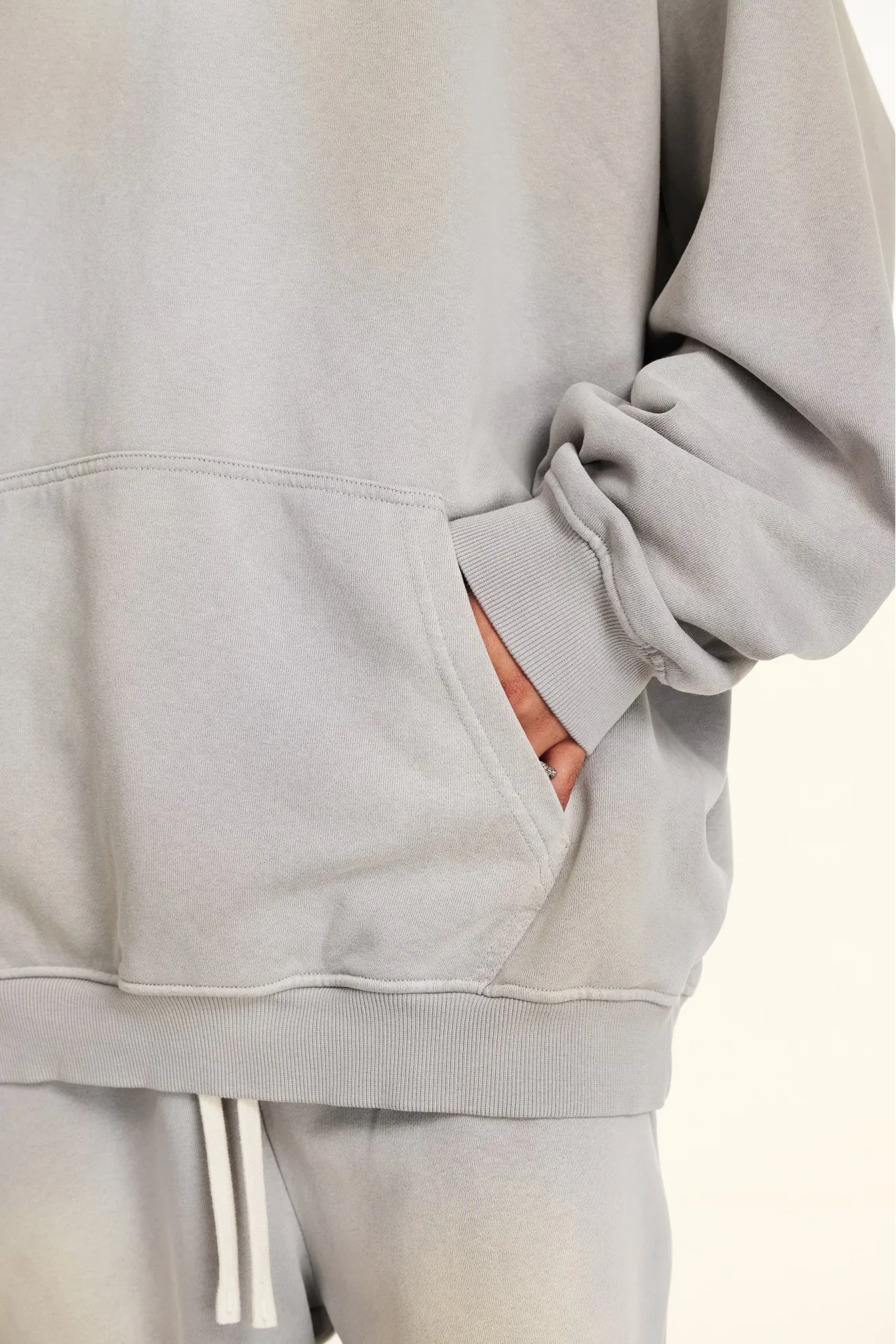 Gray tracksuit with white drawstrings on a light beige background