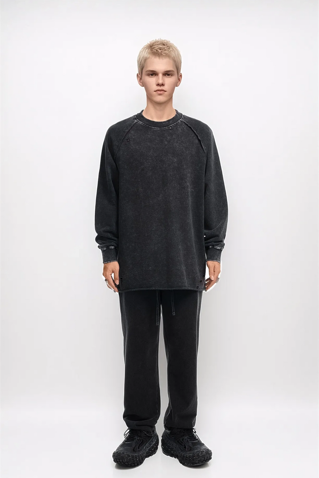 Person wearing a black oversized sweatshirt and pants on a white background