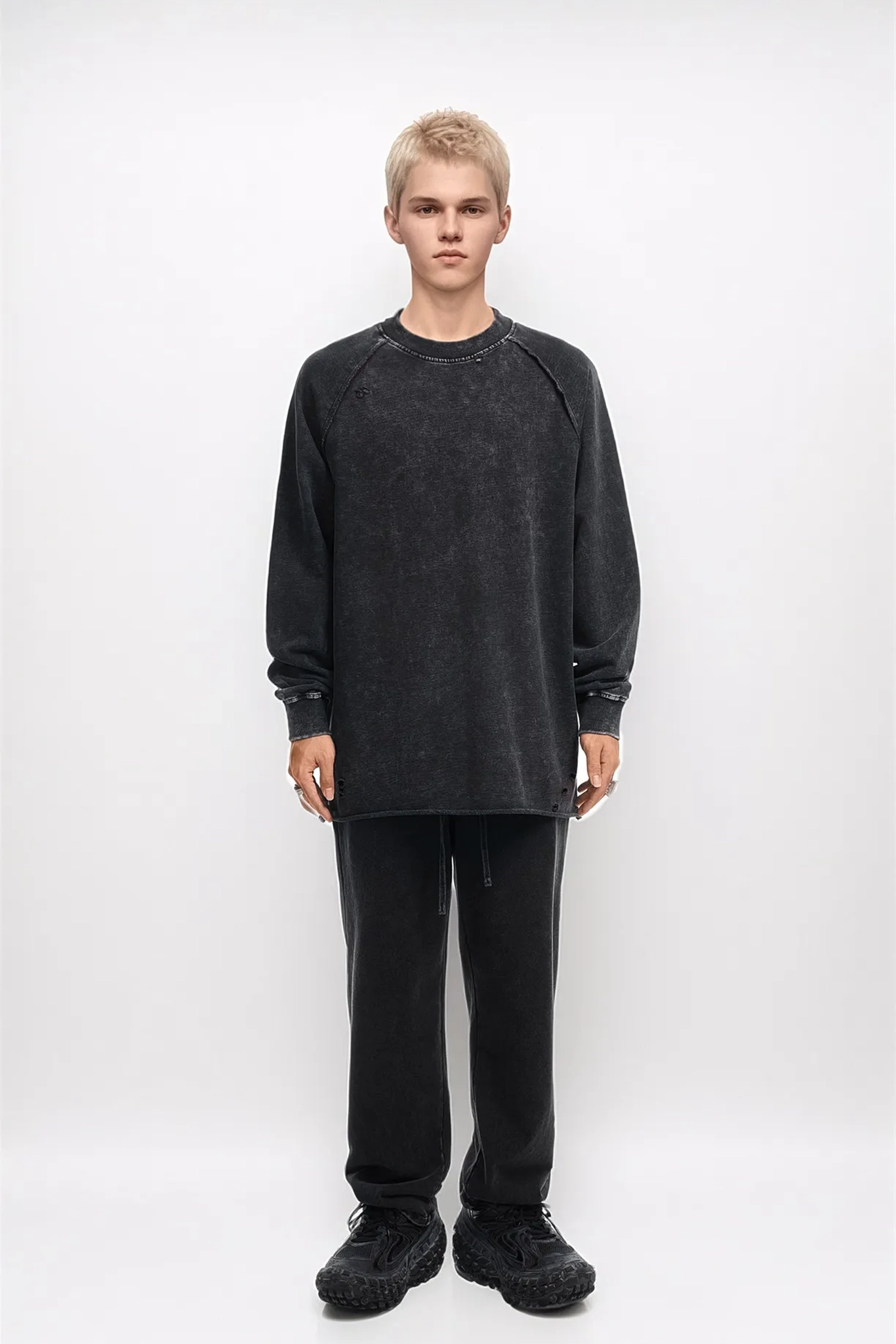Person wearing a black oversized sweatshirt and pants on a white background