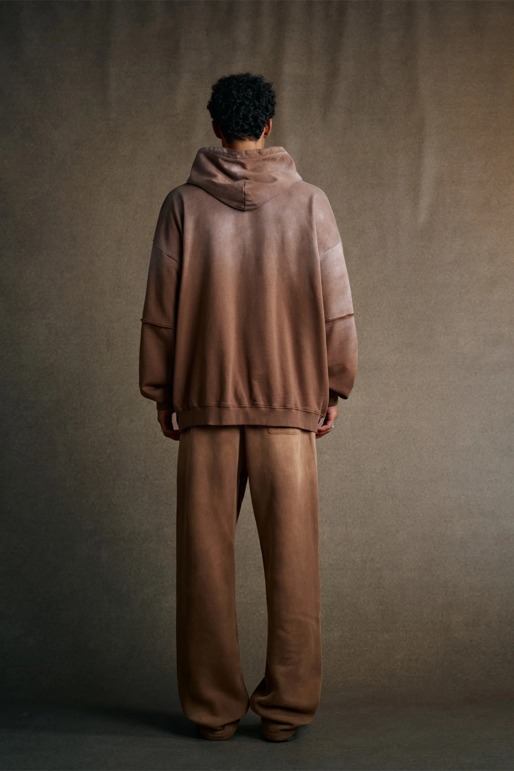 Person wearing a brown tracksuit standing against a plain background
