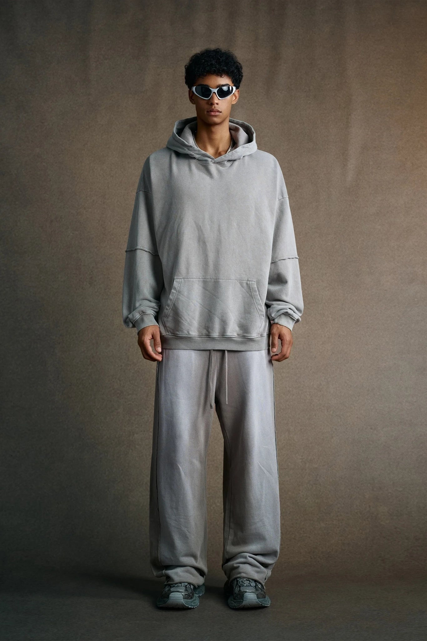 Person wearing a gray hoodie and pants against a plain background