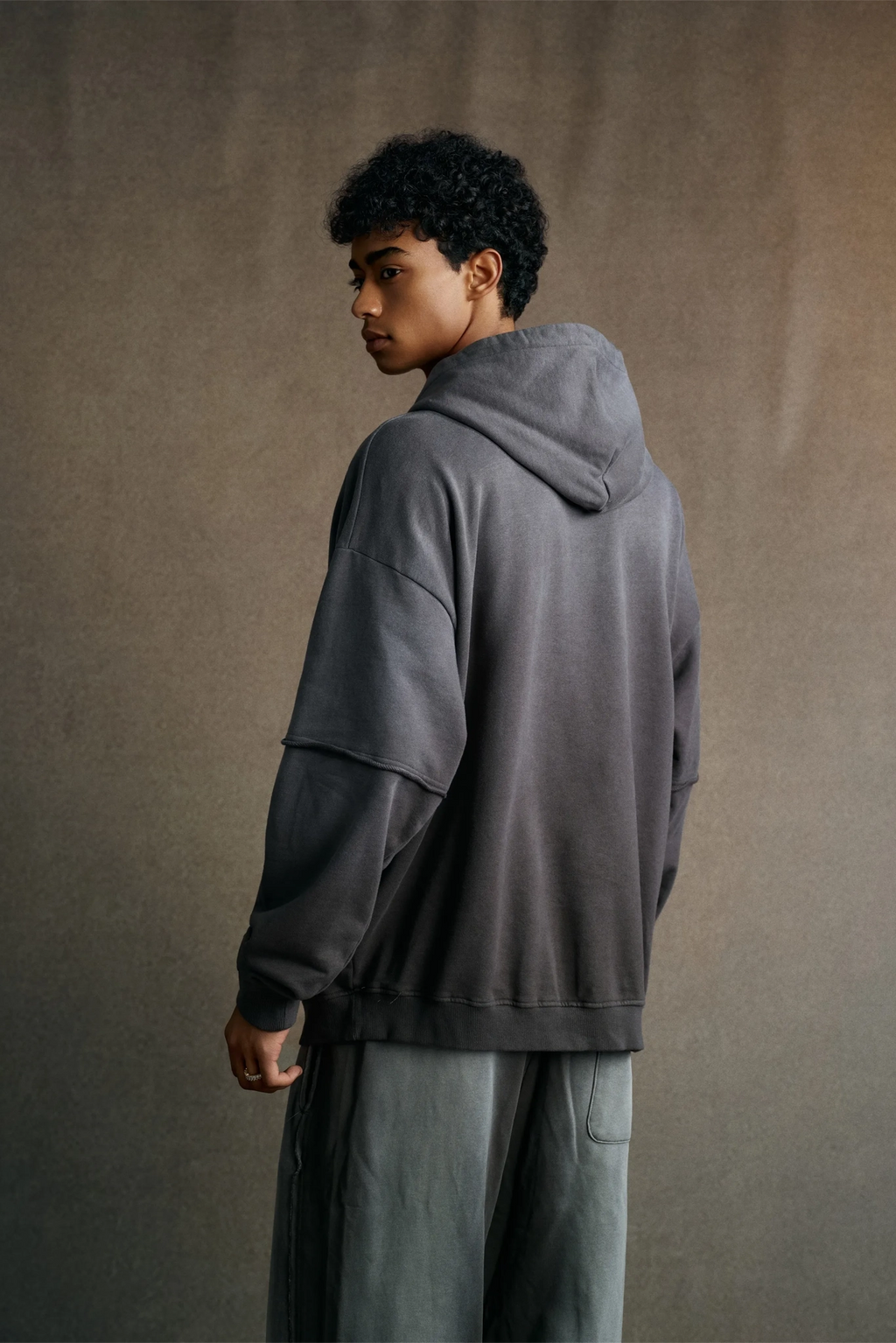 Person wearing a gray hoodie and pants against a plain background