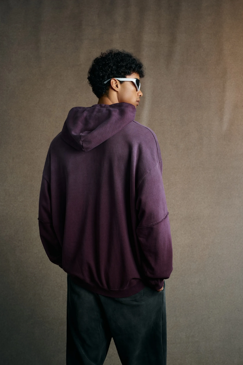 Person wearing a purple hoodie from behind against a plain background