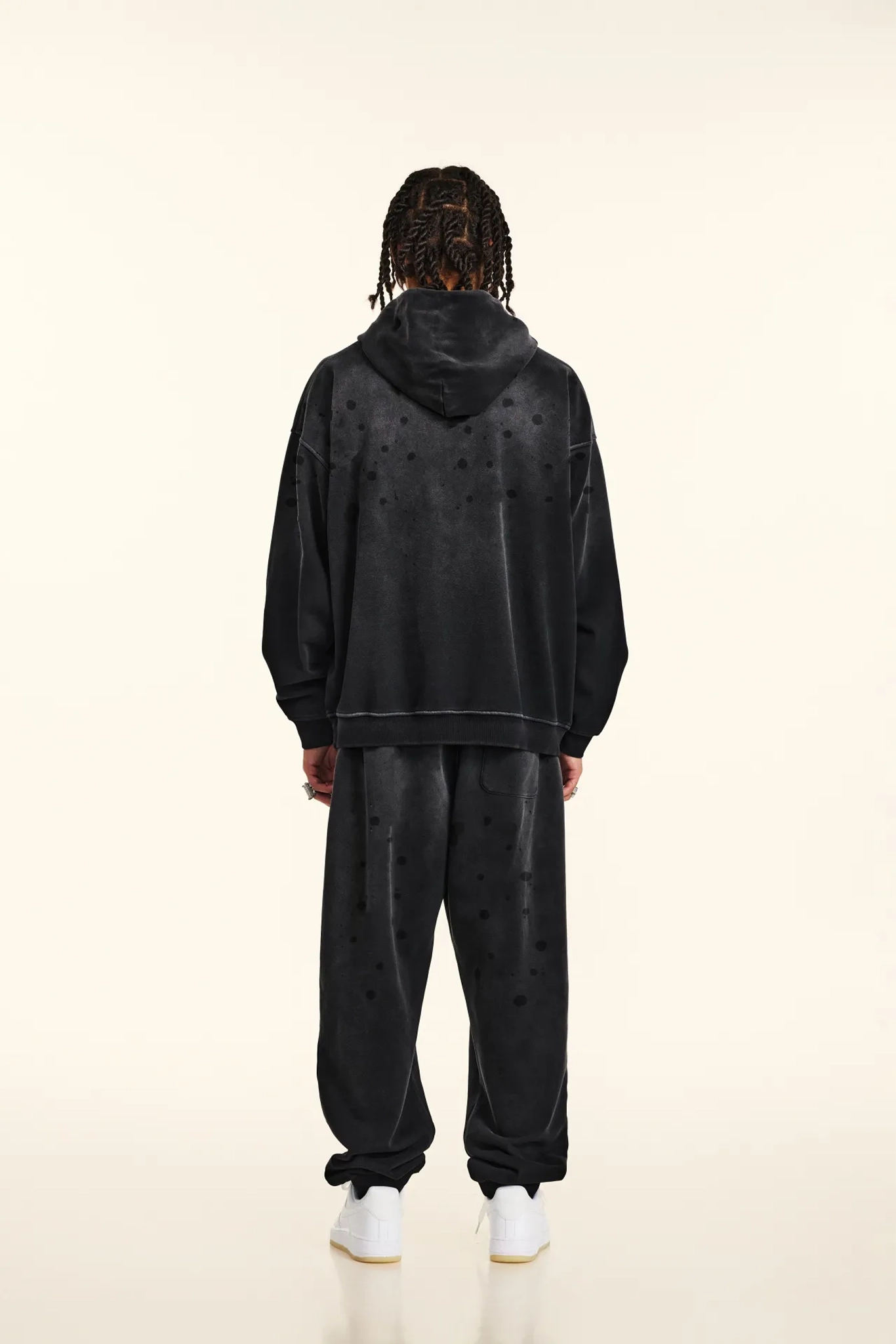 Person wearing a black hoodie and pants with star patterns on a white background