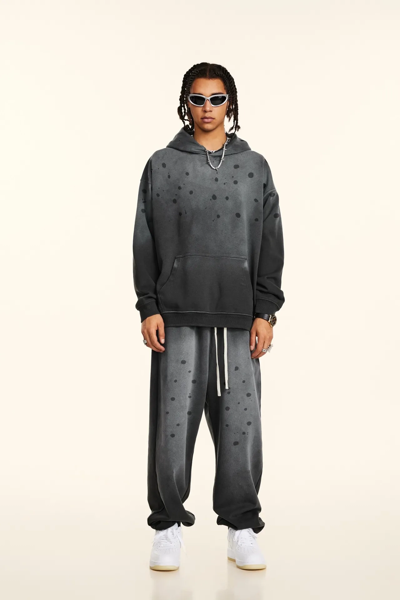 Person wearing a gray hoodie and matching pants on a white background