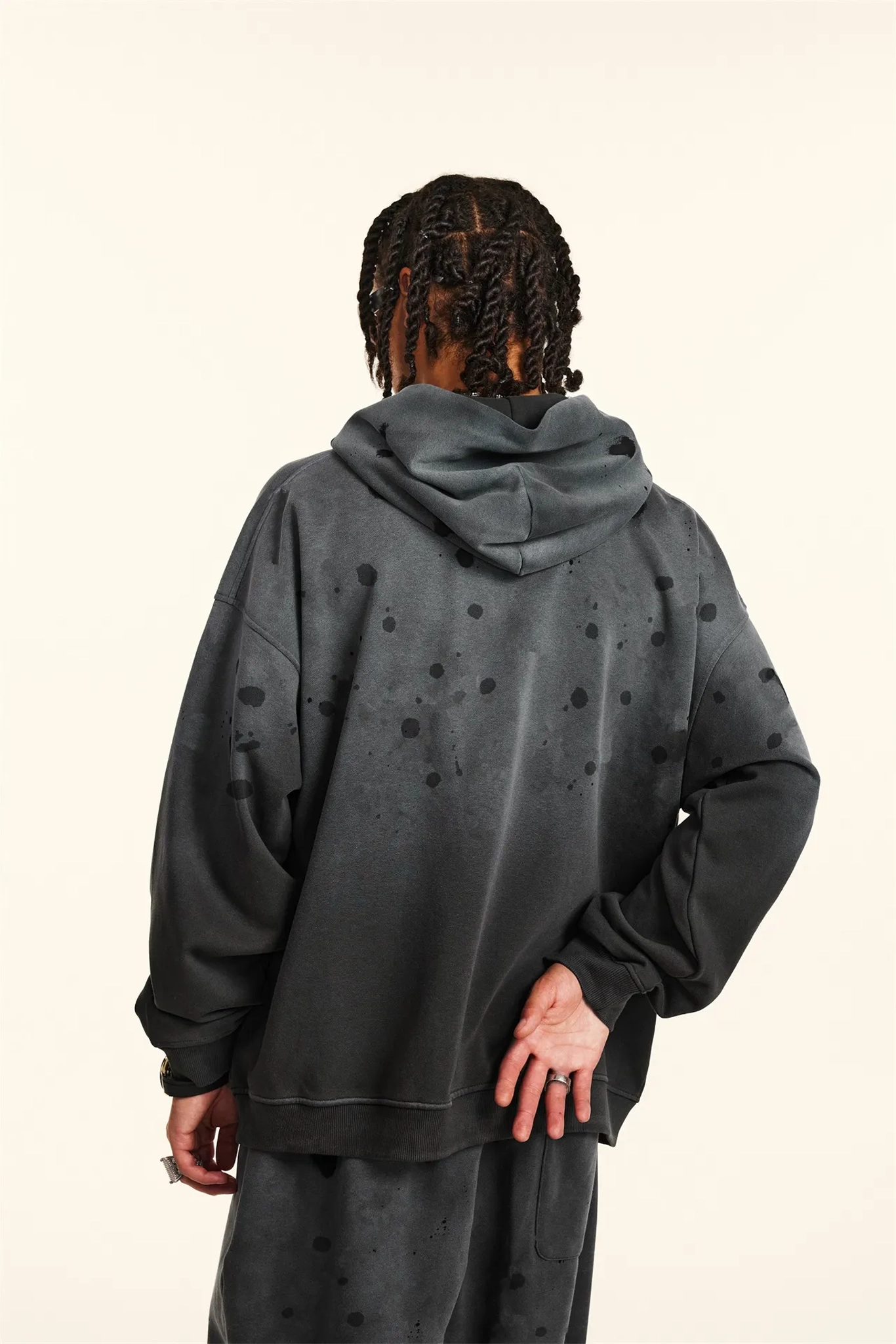 Person wearing a dark gray hoodie with subtle pattern on a beige background