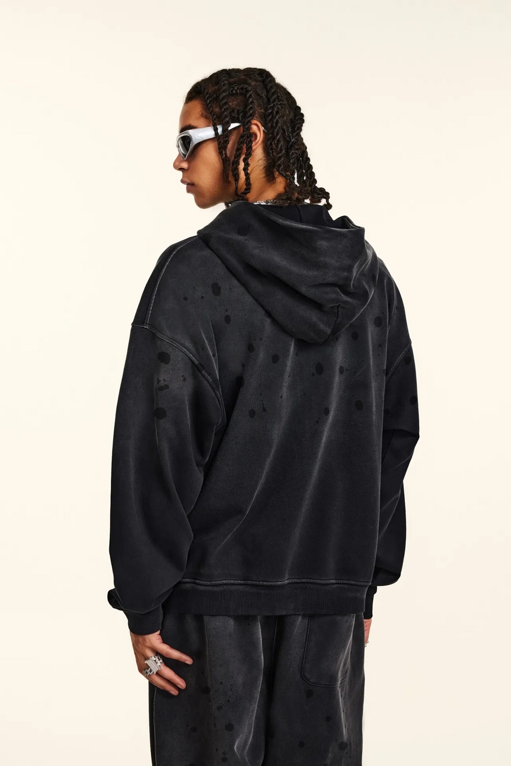 Person wearing a black hoodie with a subtle pattern on a beige background