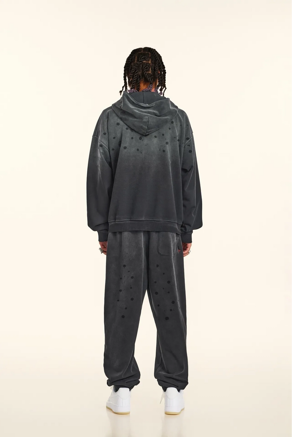 Person wearing a dark gray tracksuit with star patterns on a white background