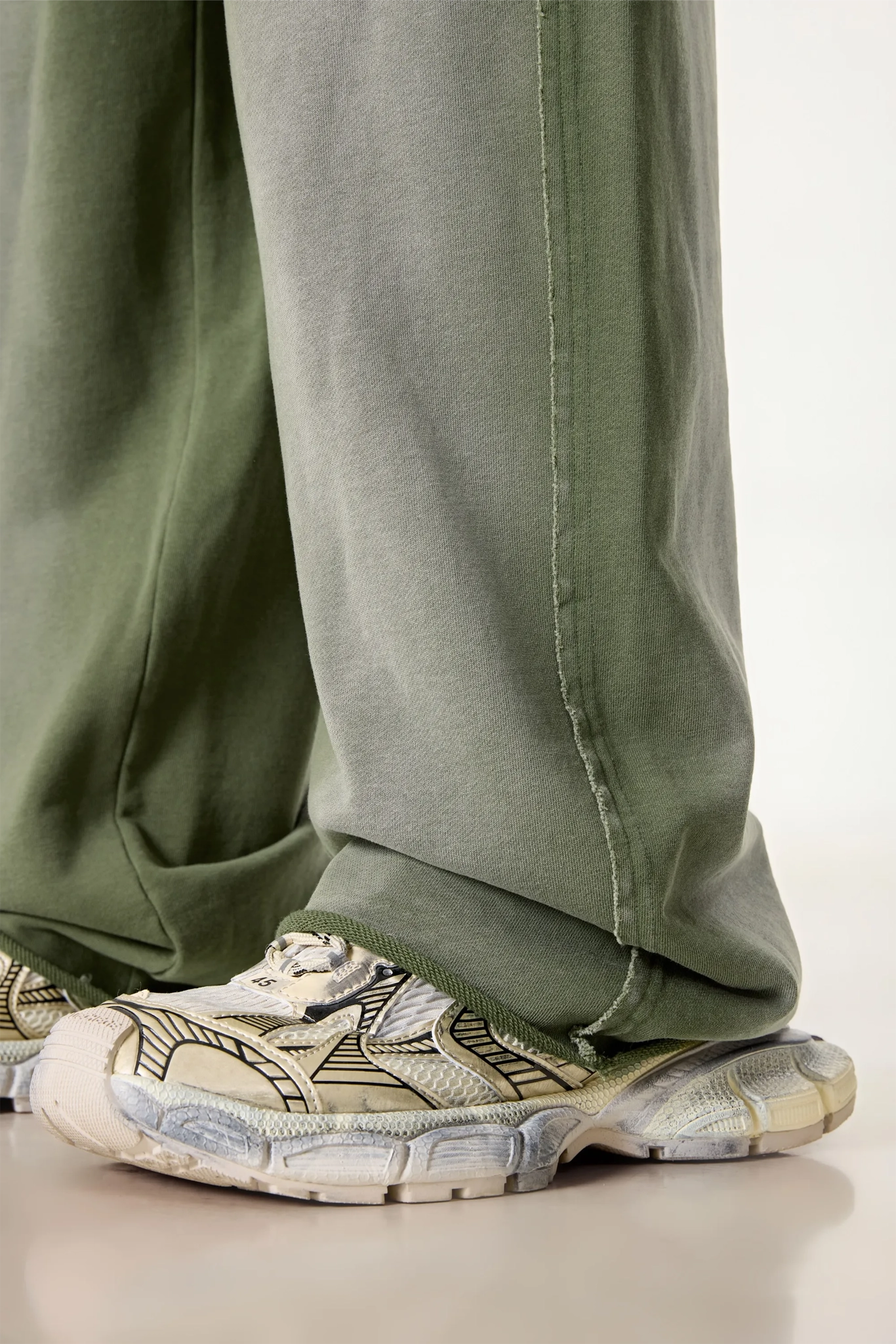 Green pants and patterned sneakers on a neutral background