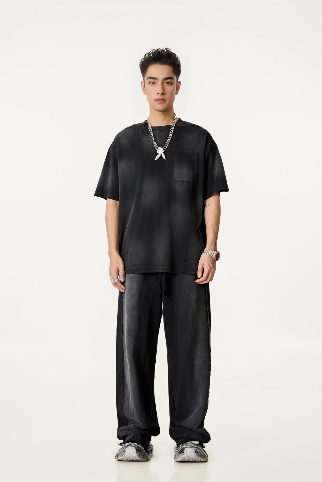 Person wearing a black outfit with a necklace on a white background