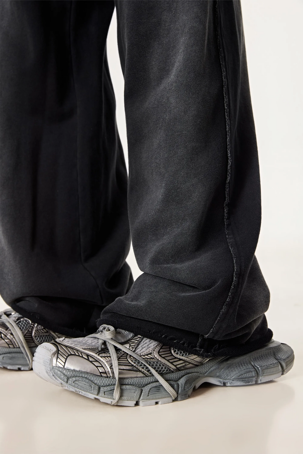 Person wearing black pants and gray sneakers on a light background