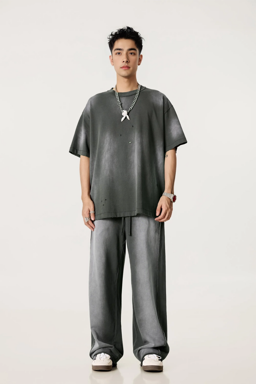 Man wearing a gray oversized t-shirt and pants on a white background
