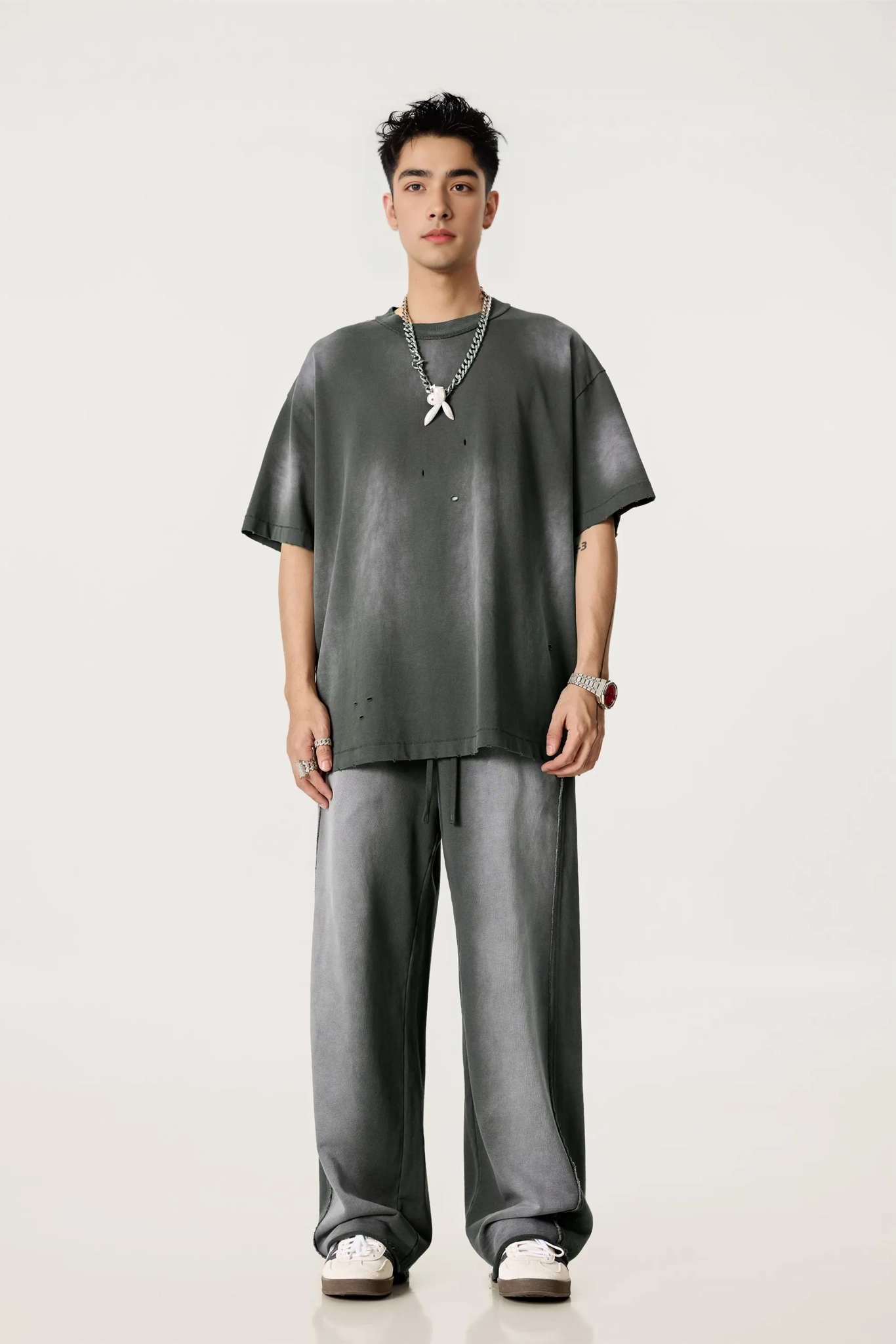 Man wearing a gray oversized t-shirt and pants on a white background