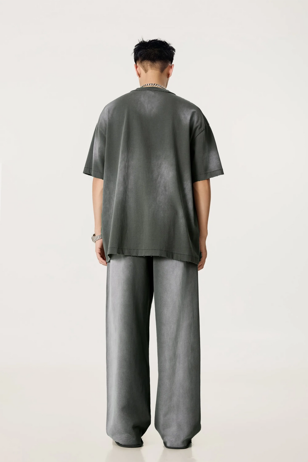 Person wearing a gray t-shirt and pants on a white background