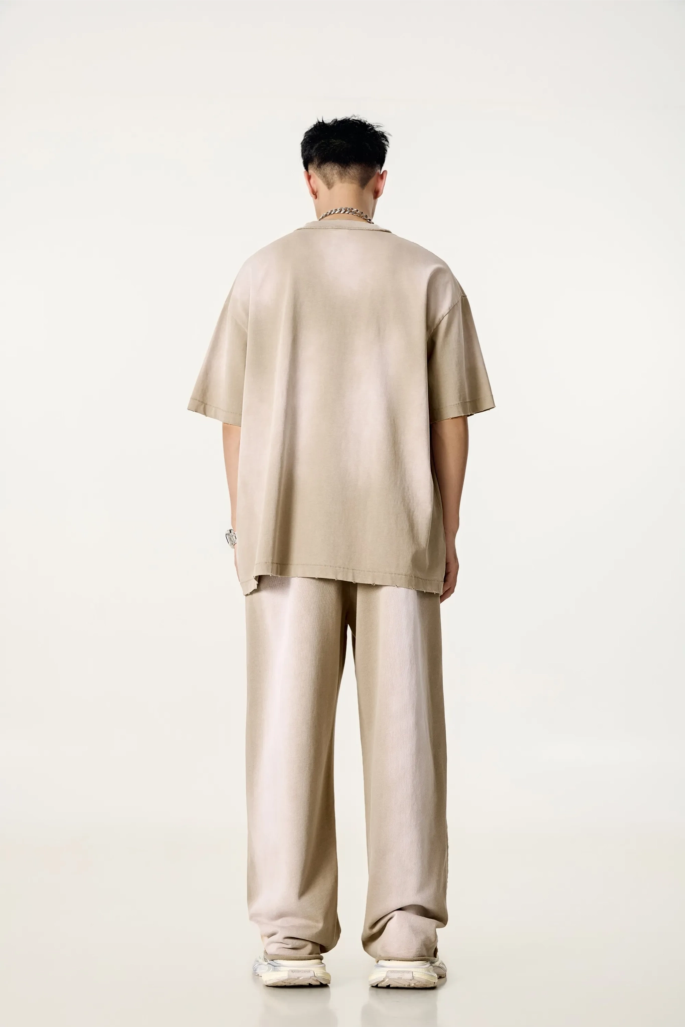 Person wearing a beige outfit standing against a white background