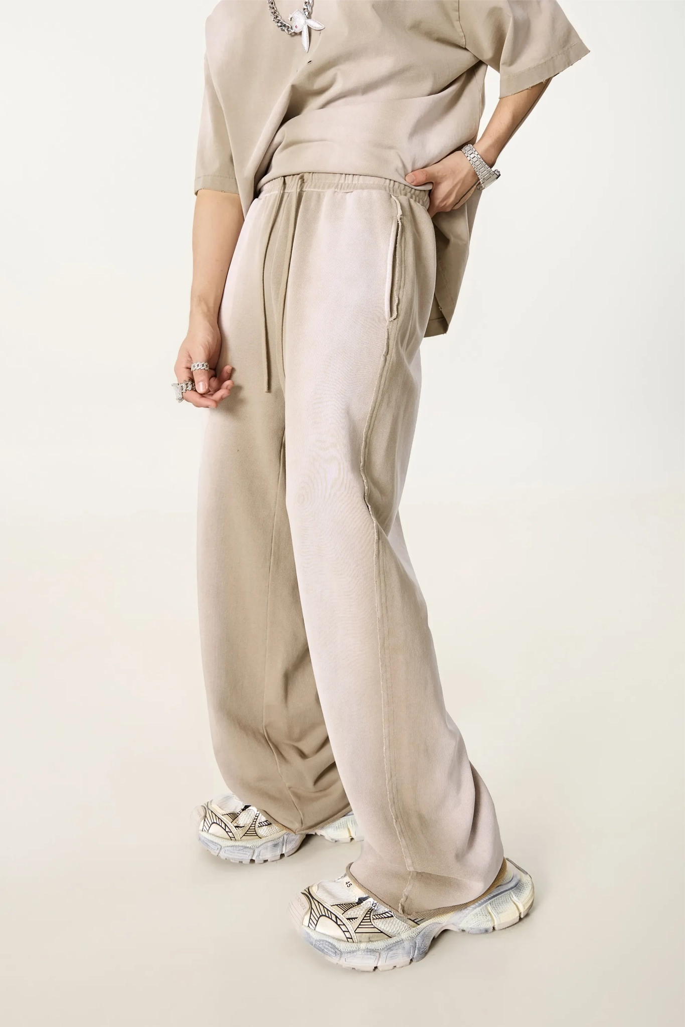 Person wearing a beige outfit with wide-leg pants on a plain background