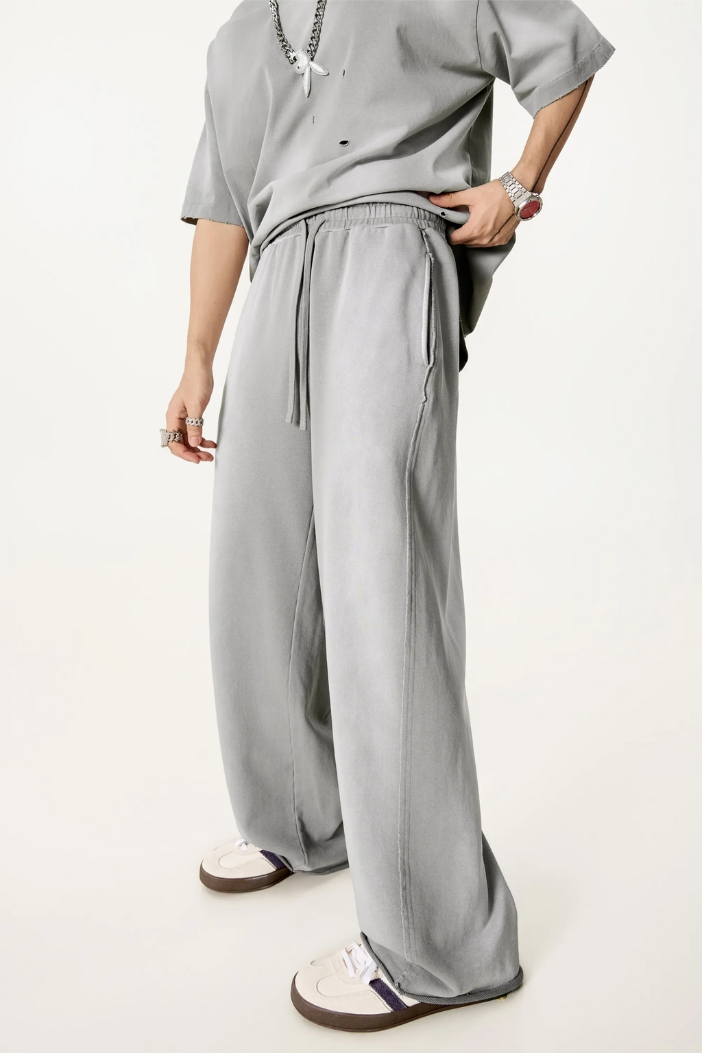 Person wearing a gray outfit with wide-leg pants on a white background