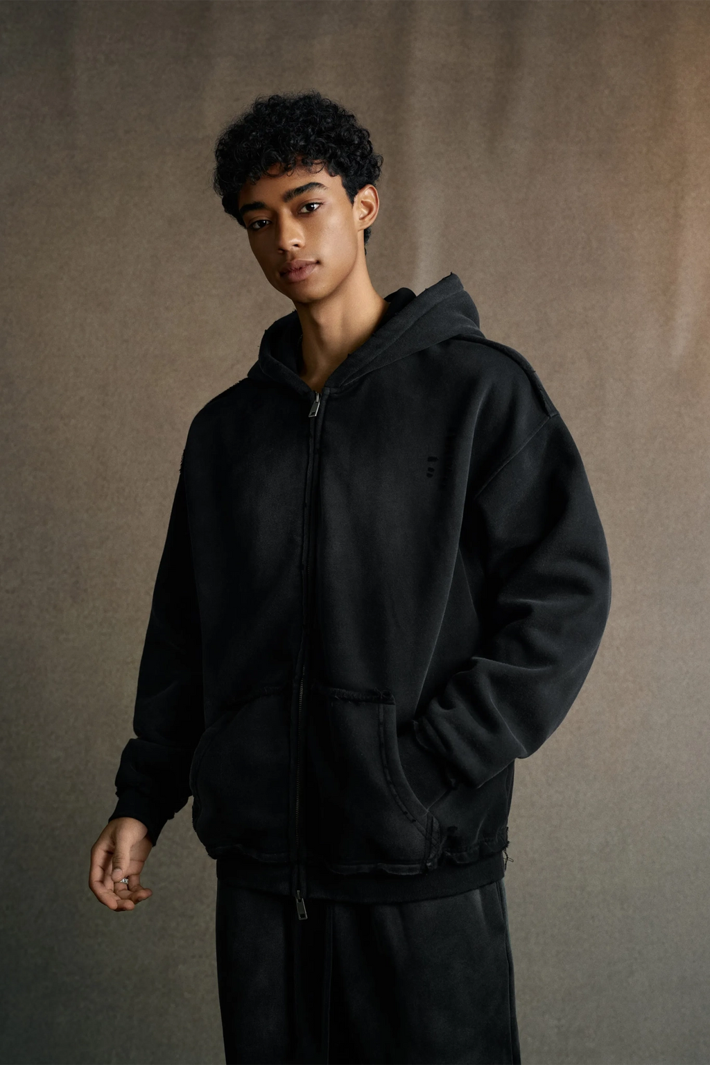 Person wearing a black hoodie against a plain background