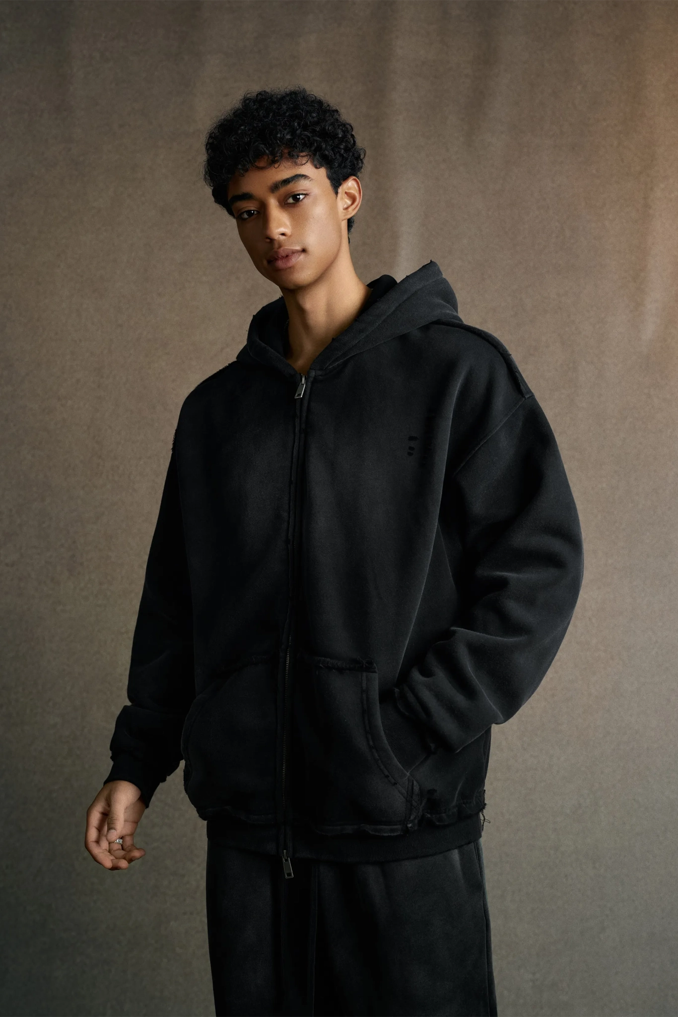Person wearing a black hoodie against a plain background