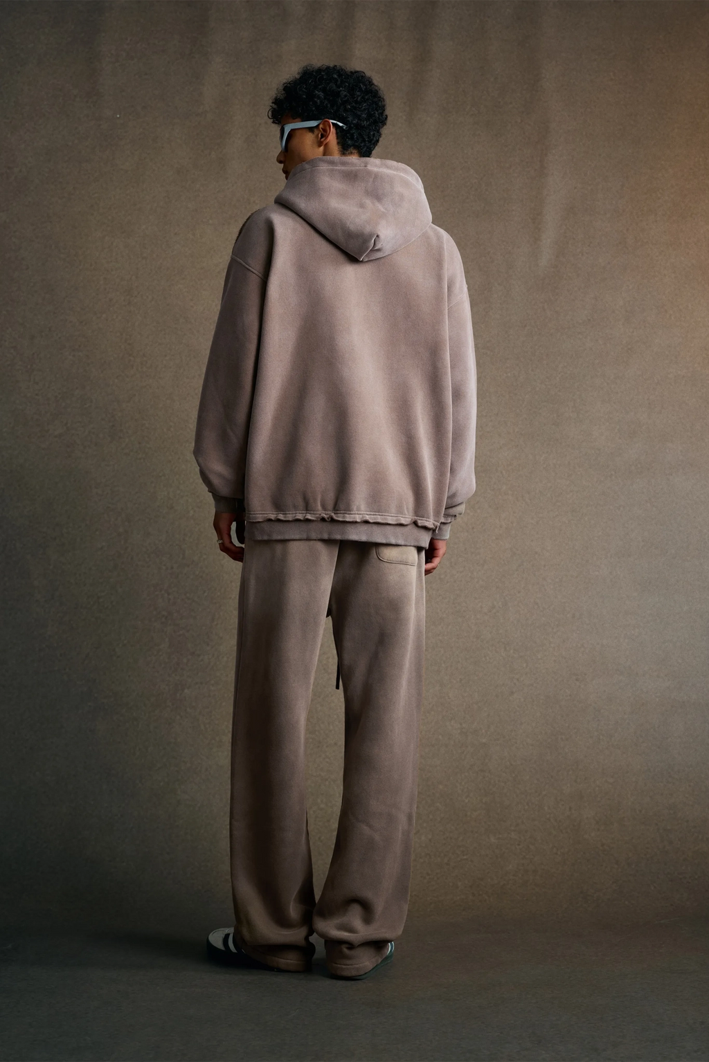 Person wearing a beige hoodie and pants against a plain background