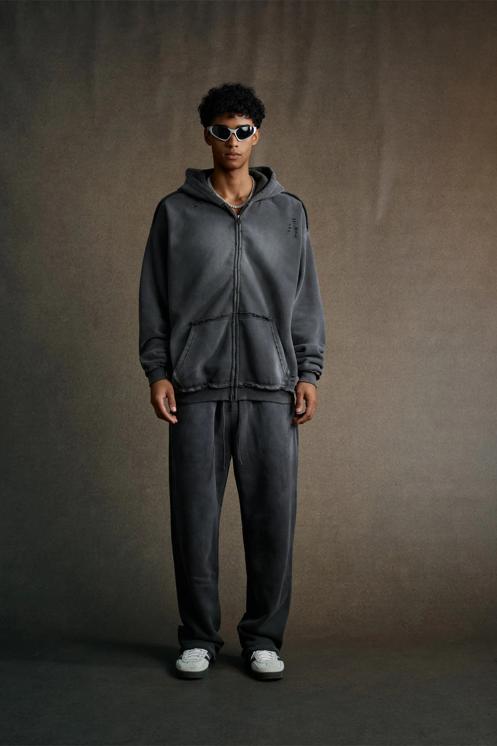 Person wearing a gray tracksuit against a plain background