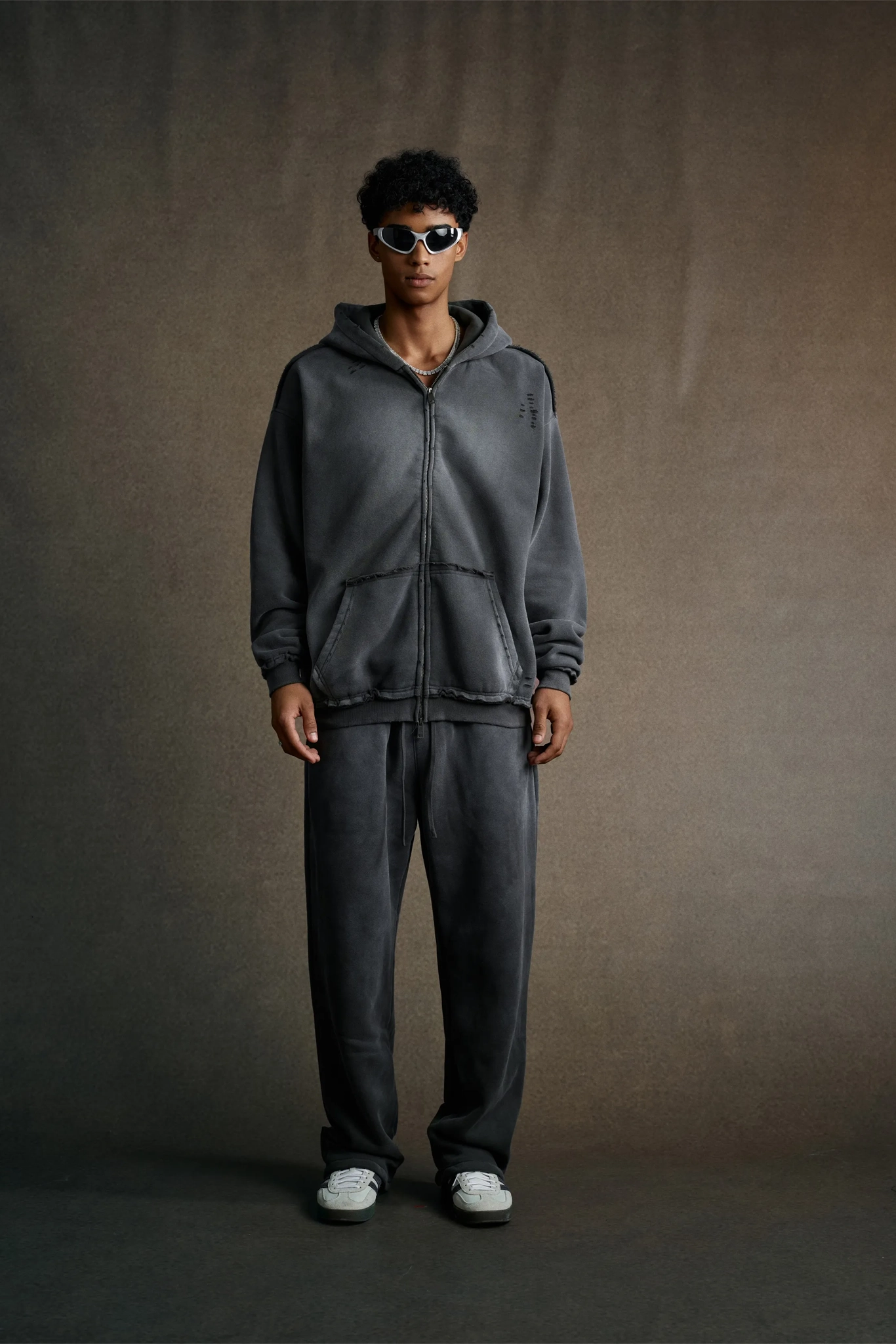 Person wearing a gray tracksuit against a plain background